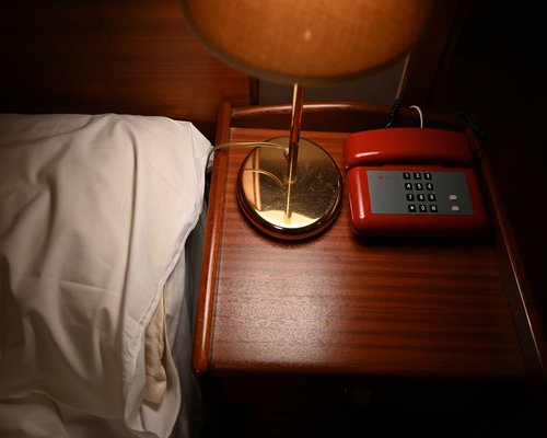A smartphone left on a bedside table beside a reading lamp