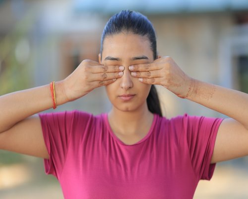 A person closing their eyes and taking a deep breath