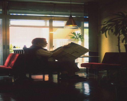 A person reading a book in a cafe with soft ambient light filtering through the window